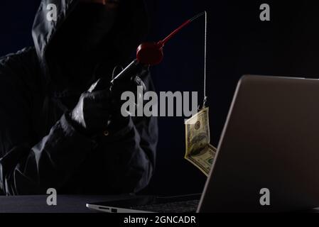Internet fraud using computer technology, stealing money on the Internet, stealing credit card data. Hacker caught a dollar bill of money on the bait Stock Photo