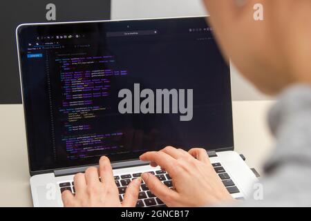 A programmer coding on a laptop in the workplace Stock Photo
