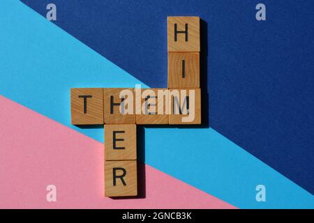 Him, Her, Them, gender pronouns in wooden alphabet letters in crossword form isolated on pink and blue. Stock Photo