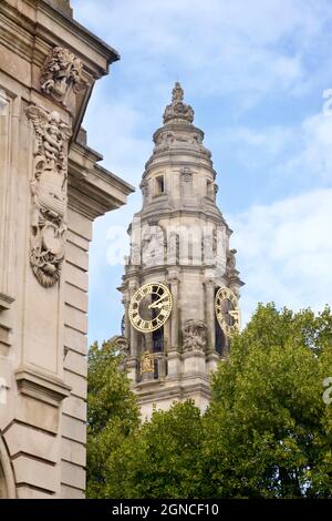 Clocktower, City Hall, Cardiff, Wales. (Welsh: Neuadd y ddinas) is a civic building in Cathays Park. Serving as Cardiff's centre of local government, it was built as part of the Cathays Park civic centre development and opened in October 1906. Built of Portland stone, it is an important early example of the Edwardian Baroque style. Stock Photo