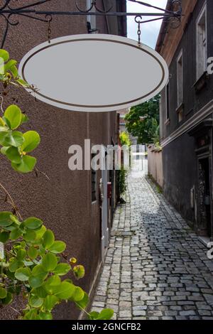 The blank signboard hanging over a narrow street Stock Photo