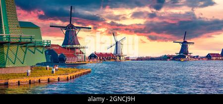 Panorama of authentic Zaandam mills on the water canal in Zaanstad village. Colorful spring sunset in  Netherlands, Europe. Artistic style post proces Stock Photo