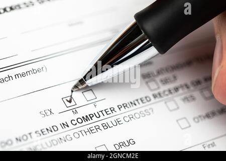 Person checking the male gender box on a document form with black pen Stock Photo