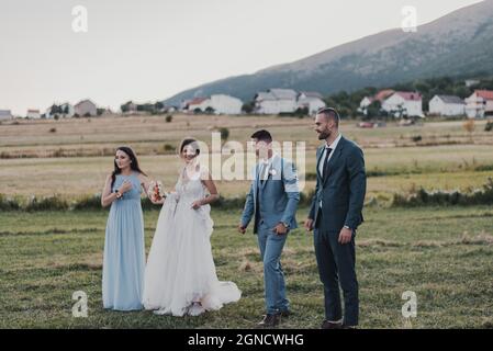 Cheerful married couple with their friends having fun in a hayfield on the wedding day Stock Photo