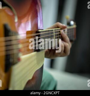 Closeup photo of an acoustic Guitar. The hands of the guitar player are in focus, as well as the fretboard. The background is out of focus. Stock Photo