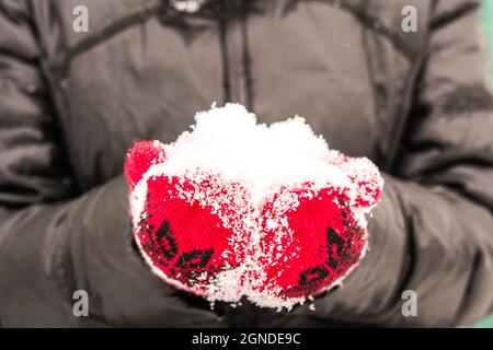 girl in red mitten holding a handful of snow Stock Photo