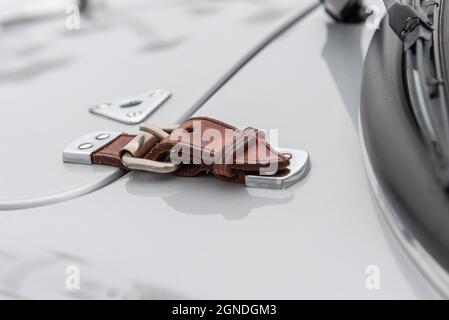 Vintage leather buckle on hood of sports car clasps the door down securly while driving. Stock Photo
