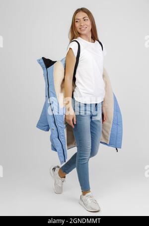 young woman in winter clothes on white background. Photo concept for advertising a down jacket. Stock Photo