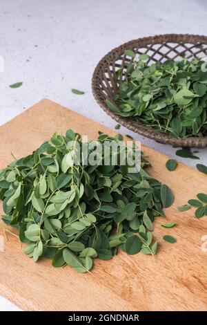 moringa or drumstick leaves on a wooden cutting board, ready to cook Stock Photo