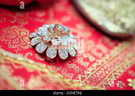 Close up of wedding rings on top of exotic jewelry on a red minangkabau ethnic fabric. No people. Selective focus.
