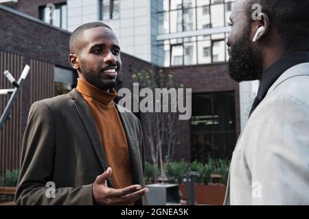 Horizontal medium portrait of two handsome African American men standing outdoors discussing new business project and sharing ideas Stock Photo
