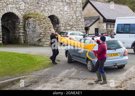 11 March 2017 A pair of male youth leaders unloading a small canoe from a car roof rack on a dull spring afternoon in Ballintoy harbour on the Atlanti Stock Photo