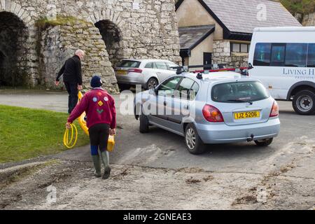 11 March 2017 A pair of male youth leaders unloading a small canoe from a car roof rack on a dull spring afternoon in Ballintoy harbour on the Atlanti Stock Photo