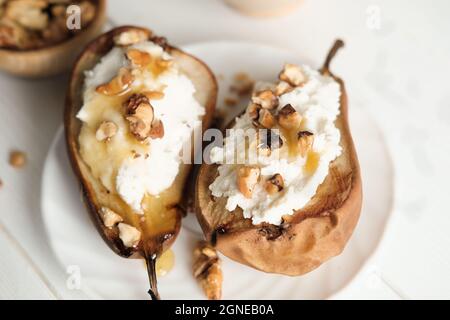 top view of sweet pears stuffed with cream cheese and nuts. grilled fruits as vegetarian dessert. white rustic table. honey topping Stock Photo