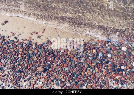 natural background of clean sea water and colorful pebbles on sunny day Stock Photo