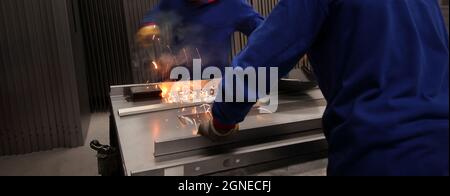 Two mature men working as welders in a metal fabrication factory. Stock Photo