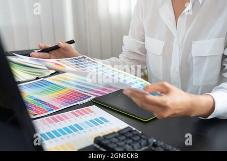 creative graphic designer choosing color scale for editing artwork while working in office Stock Photo