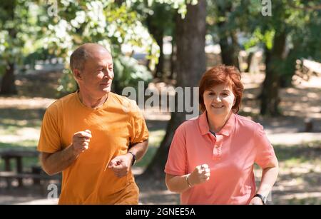 Happy senior couple running together in the park Stock Photo