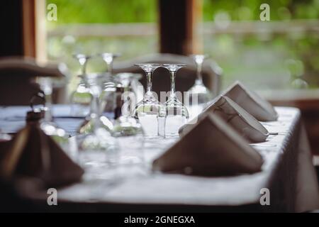 Shallow depth of field (selective focus) image with a restaurant table ready to receive customers. Empty glasses and tableware. Stock Photo