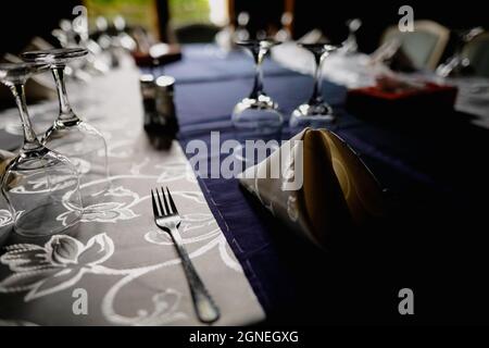 Shallow depth of field (selective focus) image with a restaurant table ready to receive customers. Empty glasses and tableware. Stock Photo
