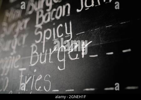 Bucharest, Romania - September 23, 2021: Shallow depth of field (selective focus) image with a restaurant menu written with chalk on a blackboard. Stock Photo