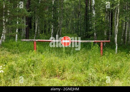 Closed barrier and prohibition sign near the forest. Entry into the forest is prohibited. Stock Photo
