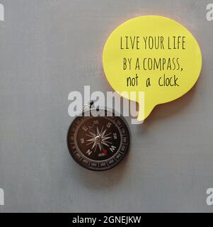 Motivational and inspirational quotes. Compass and yellow bubble speech with quotes LIVE YOUR LIFE BY A COMPASS, NOT A CLOCK. Stock Photo
