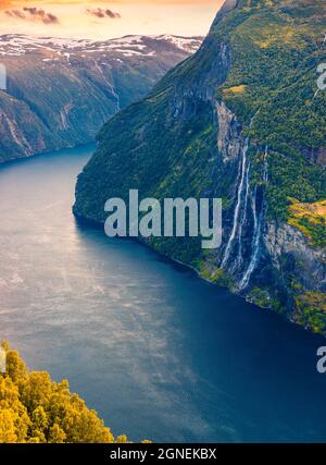 Spectacular sunrise scene of Sunnylvsfjorden fjord, Geiranger village location, western Norway. Aerial view of famous Seven Sisters waterfalls. Beauty Stock Photo