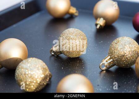 Small golden sparkling Christmas balls on black tray. New year decorations. Close up of Xmas toys. Holiday menu. Wallpaper and postcard picture Stock Photo