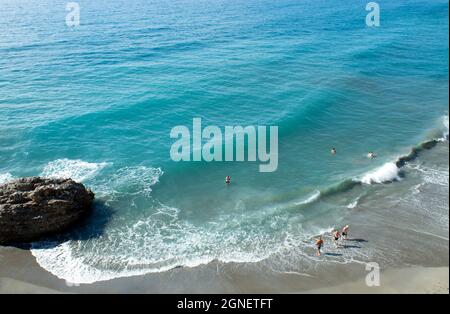 Nerja - Spain - September 22 2021 : Summer beach scene Dramatic landscape view of pristine sands Holiday makers enjoy the beautiful coast and blue sea Stock Photo