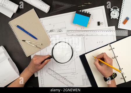 Mechanical drawing on sheets of paper. Hands on the table top view. Workflow of an architect, engineer. Write and draw. Ruler, pencil, notebook Stock Photo