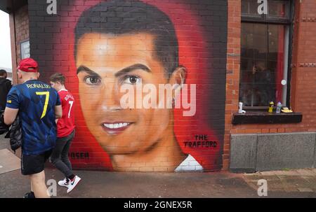 Manchester United fans near a mural of Cristiano Ronaldo before the Premier League match at Old Trafford, Manchester. Picture date: Saturday September 25, 2021. Stock Photo