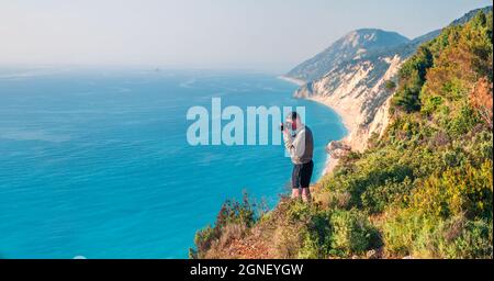 Photographer takeі picture from the top of the cliff on west coast of Lefkada island, Greece, Europe. Spectacular morning seascape of Ionian Sea. Trav Stock Photo