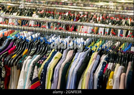 Crowded clearance section in a clothing store, with various colorful  garments placed tightly on racks in no particular order; fast fashion  concept Stock Photo