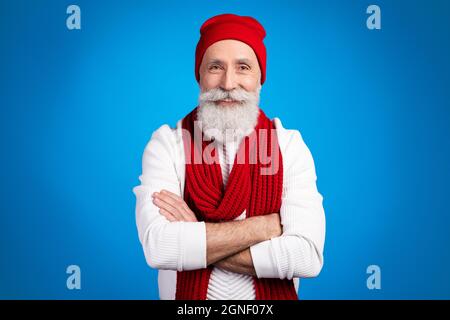 Photo of sweet cute age gentleman wear white sweater red headwear arm crossed smiling isolated blue color background Stock Photo