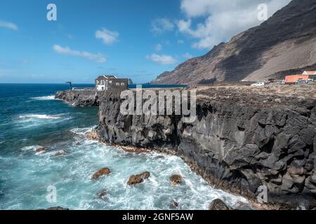 Volcanic cliff in Las Puntas with a small hotel in the background. El Hierro island. Canary Islands Stock Photo