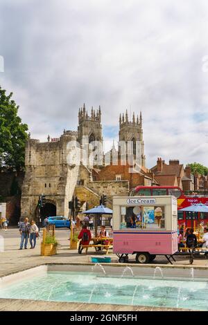 York Minster and the Monk Bar can be seen in the distance behind the ice cream van parked next to water fountain in Exhibition Square,York, UK. Stock Photo