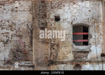 Broken red brick wall and damaged plaster on the background Stock Photo