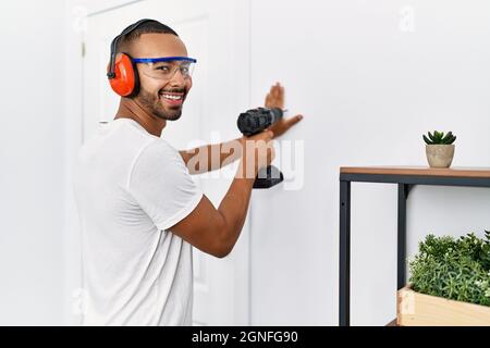 Young hispanic man smiling confident using drill at home Stock Photo