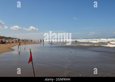 View of the seashore with red flags in a day of rough sea and big waves with people on the sandy beach, Marina Castagneto Carducci, Livorno, Tuscany Stock Photo