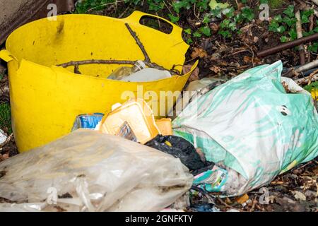 Burry Port, Wales, UK, August 21, 2021 : Rubbish waste litter of plastic bottles and containers with paper packaging garbage and bags dumped in a wood Stock Photo