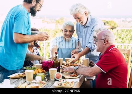 Multi generation family enjoying food and drinks party outdoors during summer holiday. Happy family spending leisure time having food at outdoors tabl Stock Photo