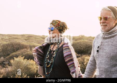 Happy senior retired couple in warm clothing enjoying hiking tour. Active elderly couple walking together and admiring scenic view during vacation hol Stock Photo