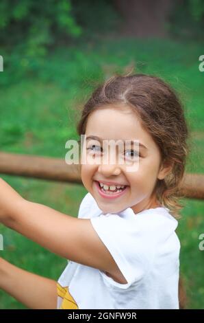 Child playing on outdoor playground. Kids plays on school or kindergarten yard.  Healthy summer activity for children in sunny weather. Cute girl smil Stock Photo