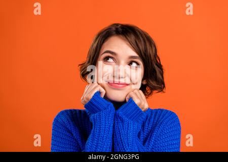 Photo of nice brunette short hairdo young lady look empty space wear blue sweater isolated on orange color background Stock Photo