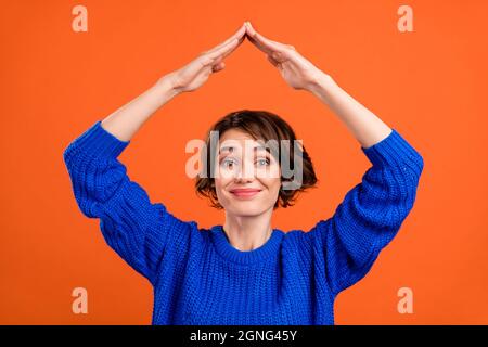 Photo of funky brunette short hairdo millennial lady hands roof wear blue sweater isolated on orange color background Stock Photo