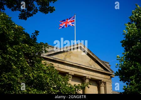 Union Jack flag flying over sunlit Harrogate council offices (Latin motto, building exterior, deep blue sky) - Crescent Gardens, Yorkshire England, UK Stock Photo