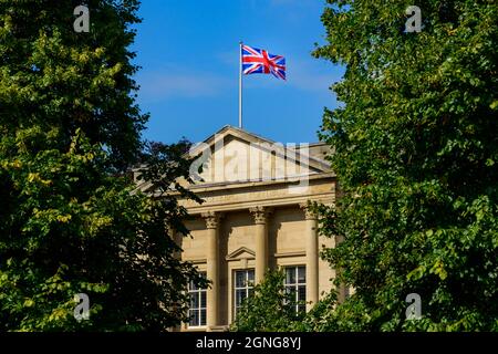 Union Jack flag flying over sunlit Harrogate council offices (Latin motto, building exterior, deep blue sky) - Crescent Gardens, Yorkshire England, UK Stock Photo