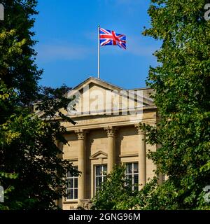 Union Jack flag flying over sunlit Harrogate council offices (Latin motto, building exterior, deep blue sky) - Crescent Gardens, Yorkshire England, UK Stock Photo