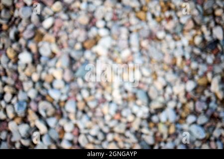 Calm river beach shore stone abstract blur. Defocused abstract background of multicolored pebbles or pebble stones on the shore closeup. Blurred Stock Photo